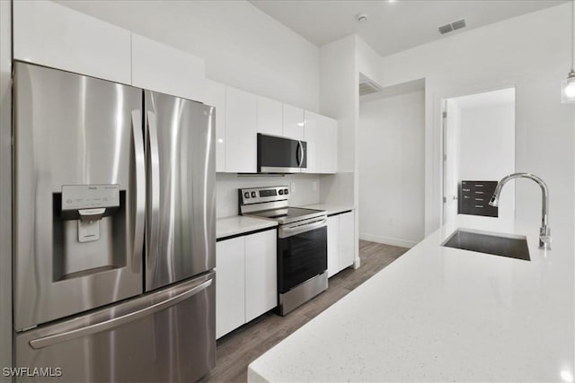 409 Columbus Blvd S, Lehigh Acres, FL 33974 - kitchen with appliances with stainless steel finishes, a sink, dark wood-type flooring, and white cabinets