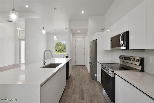 409 Columbus Blvd S, Lehigh Acres, FL 33974 - kitchen featuring appliances with stainless steel finishes, a sink, white cabinets, a kitchen island with sink, and light countertops