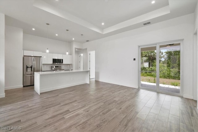 409 Columbus Blvd S, Lehigh Acres, FL 33974 - unfurnished living room with a tray ceiling, light wood-style floors, recessed lighting, and a high ceiling