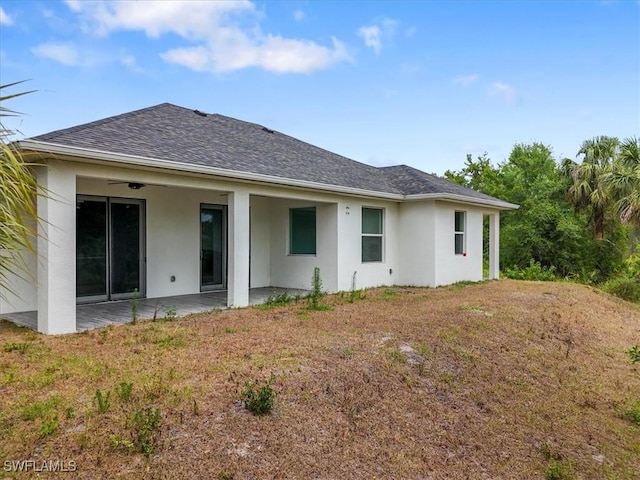 409 Columbus Blvd S, Lehigh Acres, FL 33974 - rear view of house featuring a patio, stucco siding, a shingled roof, and a lawn