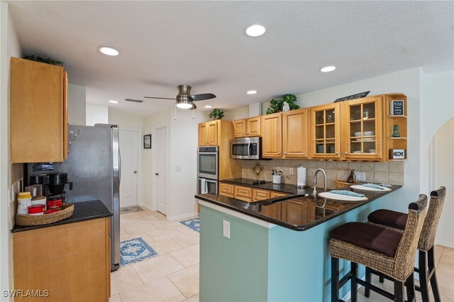 1222 SW 54th St, Cape Coral, FL 33914 - kitchen with stainless steel appliances, a peninsula, backsplash, ceiling fan, and a breakfast bar