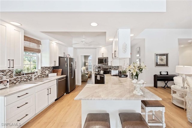 3803 Valentia Way, Naples, FL 34119 - kitchen with appliances with stainless steel finishes, a sink, light wood-type flooring, a breakfast bar, and white cabinetry