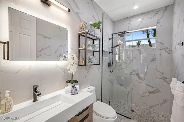 bathroom featuring toilet, a marble finish shower, and vanity