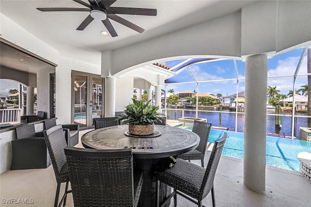 view of patio with a ceiling fan, an outdoor pool, a water view, and a lanai