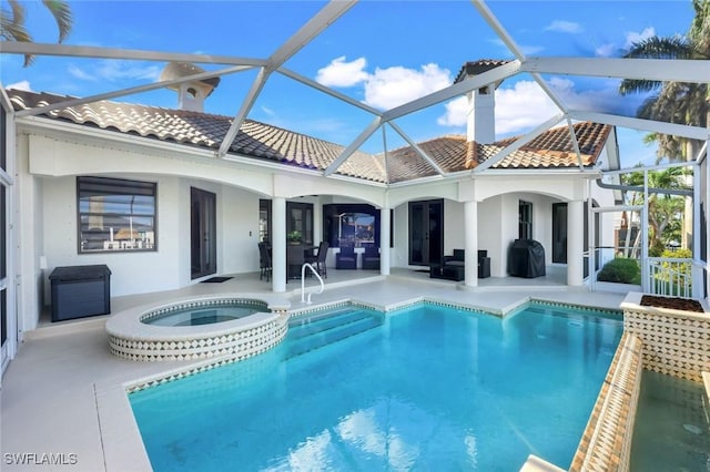 rear view of property with a tile roof, a patio, stucco siding, and glass enclosure
