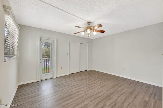 7400 College Pkwy Unit 5A, Fort Myers, FL 33907 - unfurnished bedroom with wood finished floors, access to exterior, a textured ceiling, baseboards, and ceiling fan