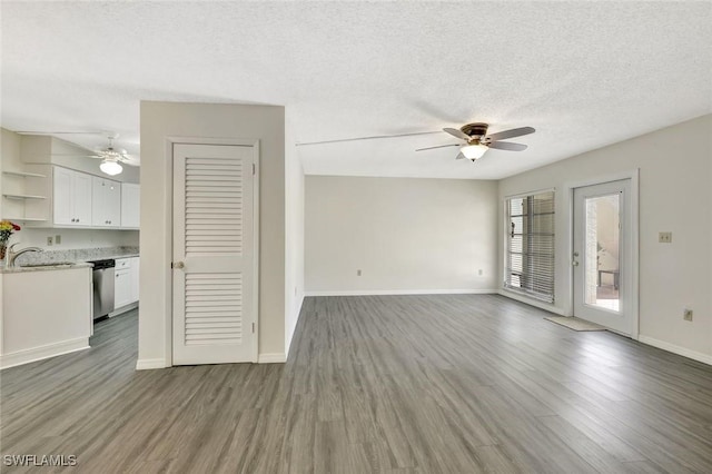 7400 College Pkwy Unit 5A, Fort Myers, FL 33907 - unfurnished living room with a ceiling fan, a sink, wood finished floors, baseboards, and a textured ceiling