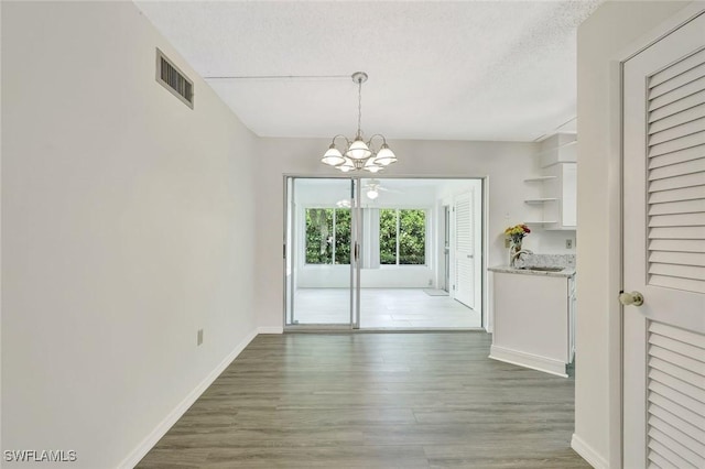 7400 College Pkwy Unit 5A, Fort Myers, FL 33907 - unfurnished dining area featuring a chandelier, wood finished floors, a textured ceiling, baseboards, and a sink