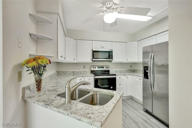 7400 College Pkwy Unit 5A, Fort Myers, FL 33907 - kitchen with stainless steel appliances, open shelves, a sink, a peninsula, and a ceiling fan
