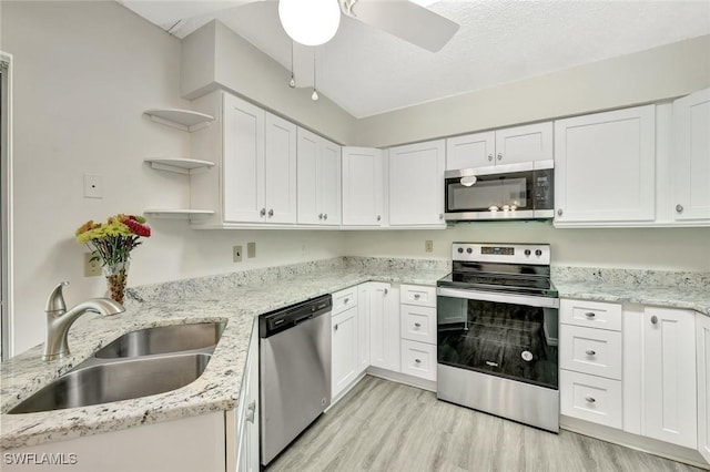 7400 College Pkwy Unit 5A, Fort Myers, FL 33907 - kitchen with appliances with stainless steel finishes, a sink, open shelves, white cabinetry, and light wood-style flooring