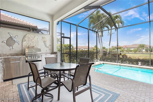 1421 Lucena Ln S, Naples, FL 34113 - outdoor pool featuring an outdoor kitchen, a patio area, glass enclosure, a grill, and outdoor dining space
