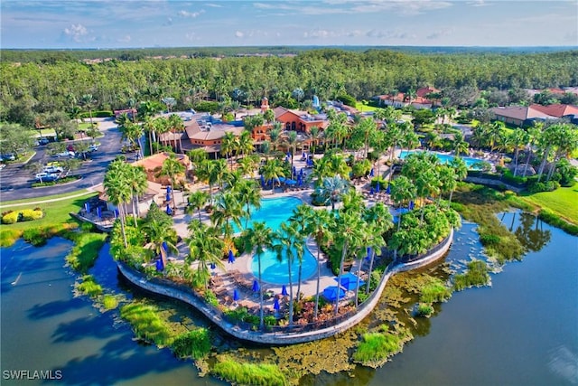 bird's eye view of a heavily wooded area, a pool, and a nearby body of water
