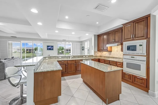 kitchen featuring white appliances, a raised ceiling, open floor plan, plenty of natural light, and recessed lighting
