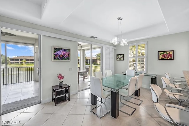 dining space featuring a chandelier, baseboards, light tile patterned floors, and a water view