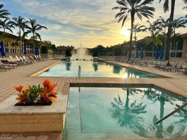 pool at dusk with a community pool and a patio