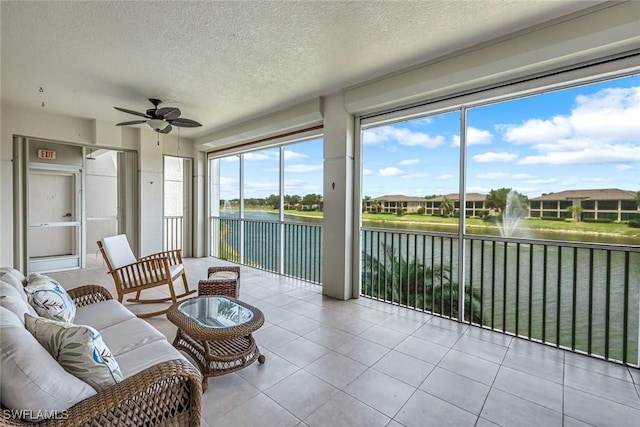 sunroom / solarium with a water view, healthy amount of natural light, a textured ceiling, and tile patterned floors