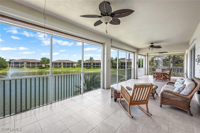sunroom featuring a ceiling fan, a textured ceiling, outdoor dining space, an outdoor hangout area, and a water view