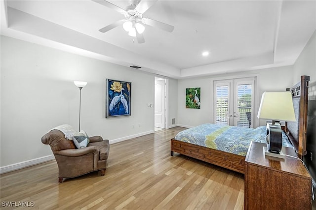 bedroom featuring a tray ceiling, access to exterior, light wood-style flooring, french doors, and baseboards