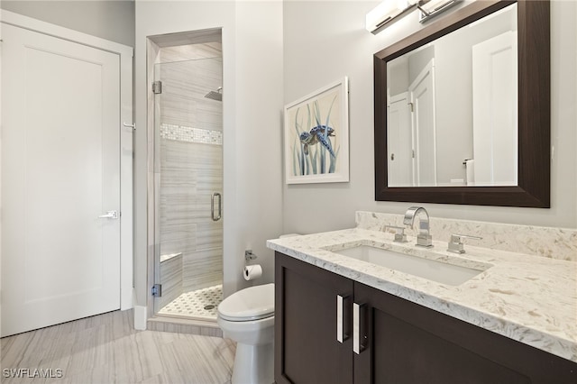 full bathroom featuring toilet, a shower stall, and vanity
