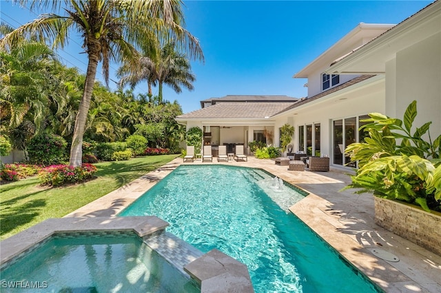 view of swimming pool featuring a patio, a lawn, and a pool with connected hot tub