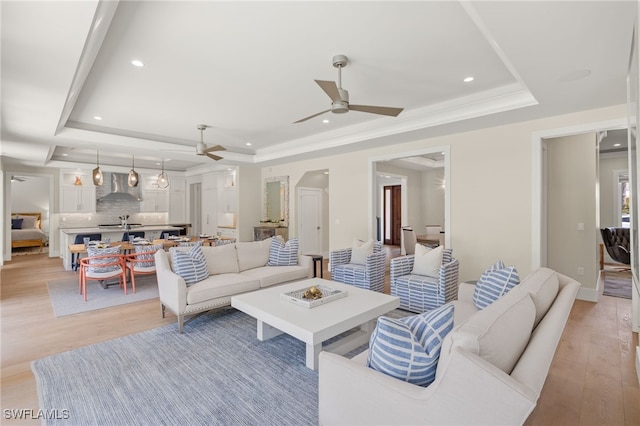 living area featuring a tray ceiling, a ceiling fan, light wood-style floors, and recessed lighting