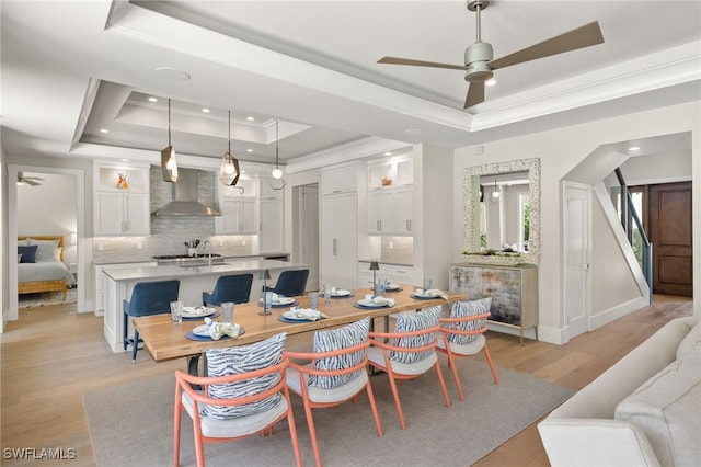 dining area with a tray ceiling, ceiling fan, ornamental molding, recessed lighting, and light wood finished floors