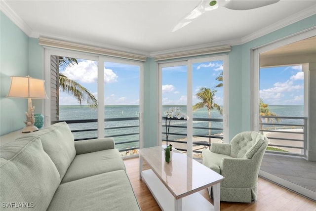 sunroom with a water view, ornamental molding, and wood finished floors