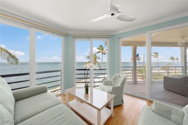 sunroom / solarium featuring a water view, crown molding, plenty of natural light, and wood finished floors