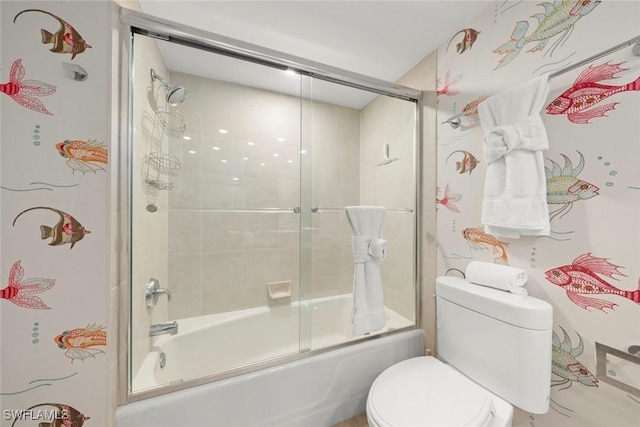bathroom featuring combined bath / shower with glass door and toilet