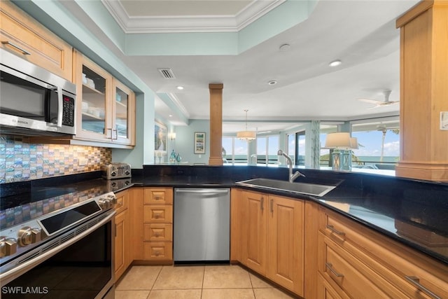kitchen with appliances with stainless steel finishes, crown molding, a sink, healthy amount of natural light, and decorative backsplash