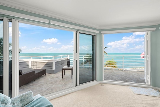 unfurnished sunroom featuring a water view, ornamental molding, and carpet