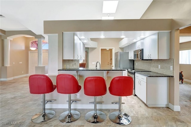 kitchen with appliances with stainless steel finishes, a kitchen bar, decorative backsplash, and a sink