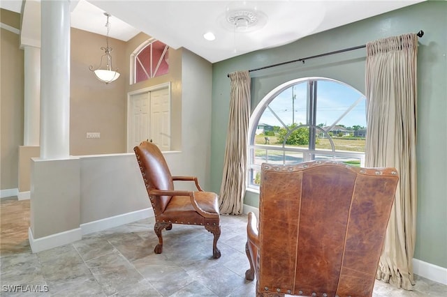 living area featuring decorative columns and baseboards