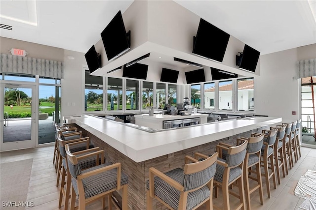 kitchen with a towering ceiling, light countertops, and a kitchen bar