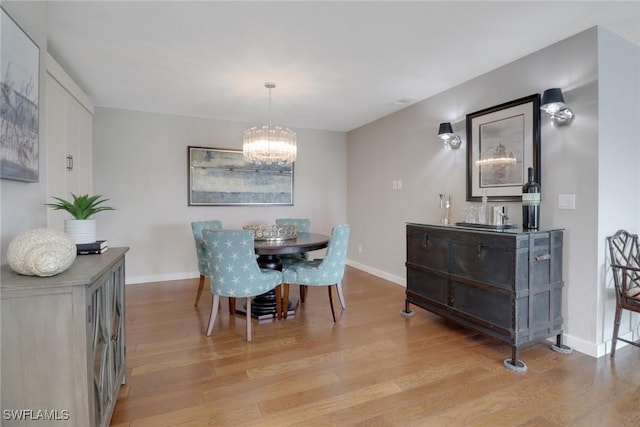 dining space featuring a chandelier, light wood-style flooring, and baseboards