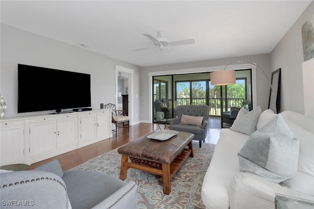 living area with a ceiling fan and dark wood-style floors