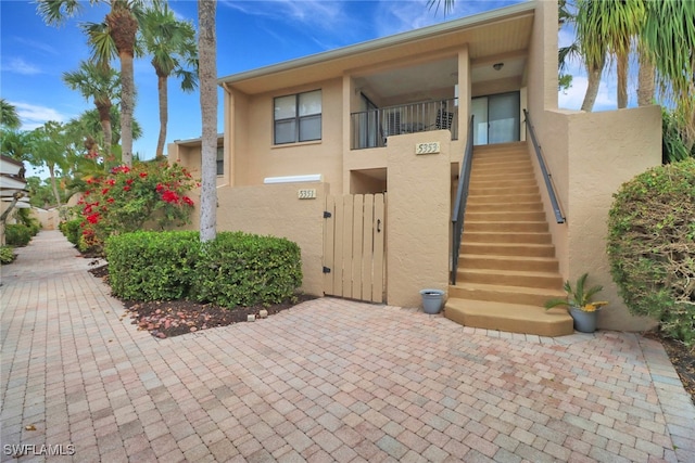 view of front of home with stairway, stucco siding, a gate, and fence