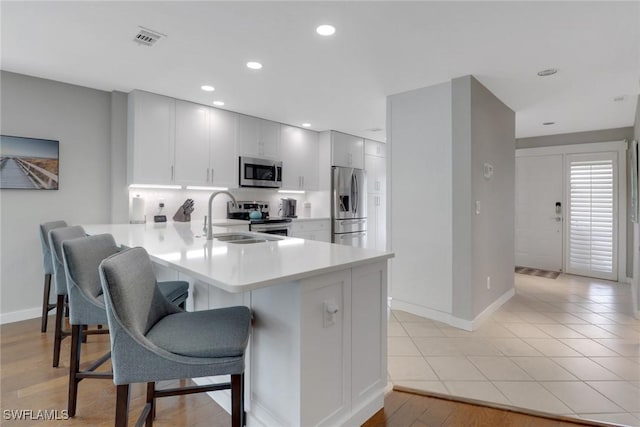 kitchen featuring appliances with stainless steel finishes, a kitchen breakfast bar, a peninsula, light countertops, and baseboards