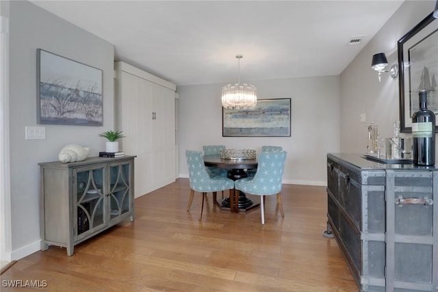 dining room with a chandelier, light wood-style flooring, and baseboards
