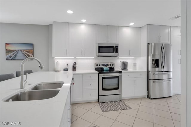 kitchen featuring stainless steel appliances, a sink, recessed lighting, white cabinetry, and light tile patterned floors