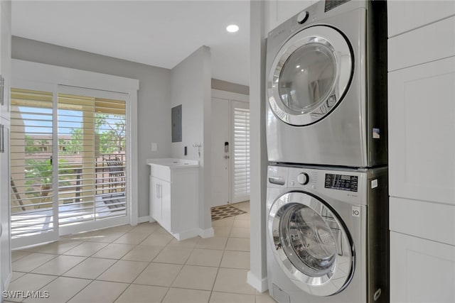 washroom with stacked washer and clothes dryer, light tile patterned floors, electric panel, and baseboards