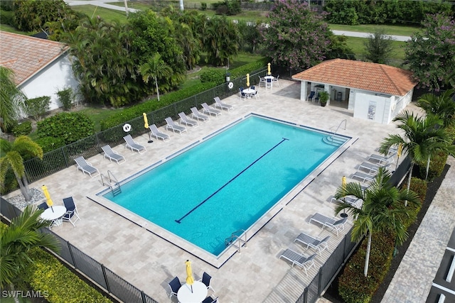 community pool featuring a patio area, fence, and an outdoor structure