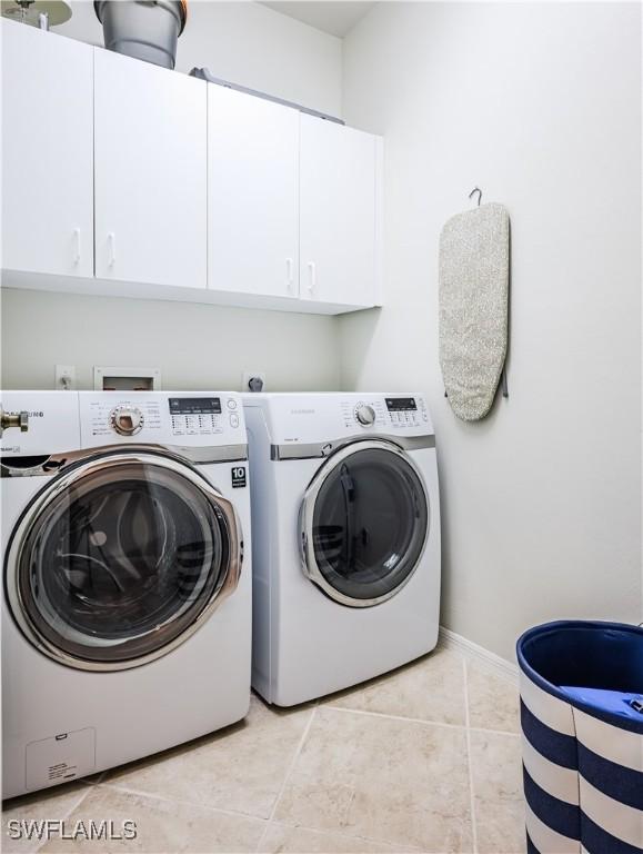laundry room with cabinet space, washing machine and clothes dryer, baseboards, and light tile patterned floors