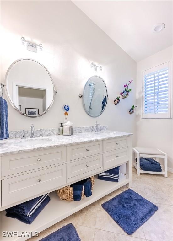 bathroom featuring double vanity, tile patterned floors, and vaulted ceiling