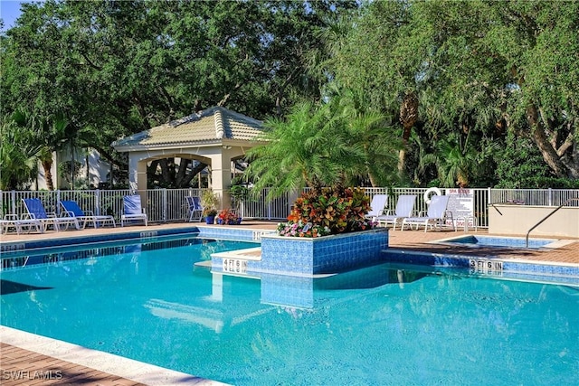 community pool featuring fence and a community hot tub