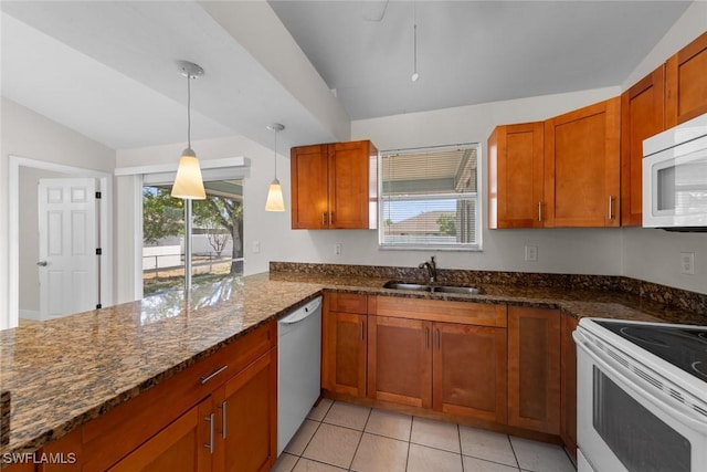 kitchen featuring vaulted ceiling, brown cabinetry, white appliances, and a sink