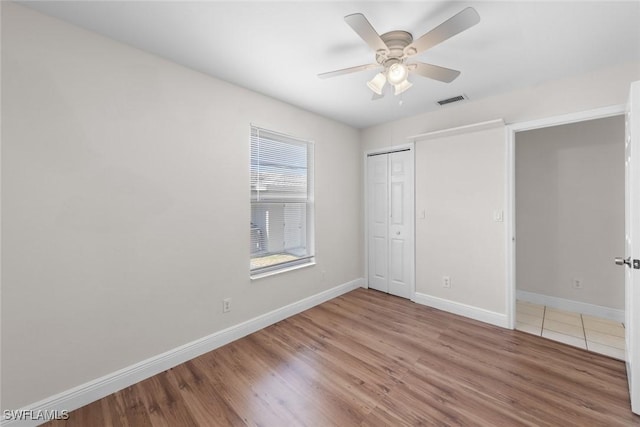 unfurnished bedroom featuring a closet, visible vents, wood finished floors, and baseboards