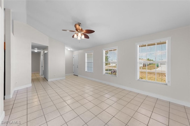 empty room with light tile patterned floors, baseboards, a ceiling fan, and lofted ceiling