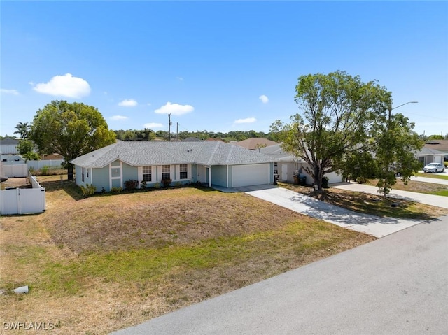 single story home featuring an attached garage, driveway, fence, and a front yard