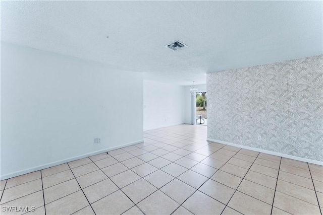 unfurnished room featuring wallpapered walls, baseboards, light tile patterned flooring, and a textured ceiling
